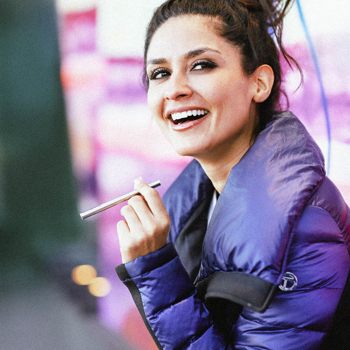 Woman in purple jacket smiling while holding HealthVape Boost vape pen