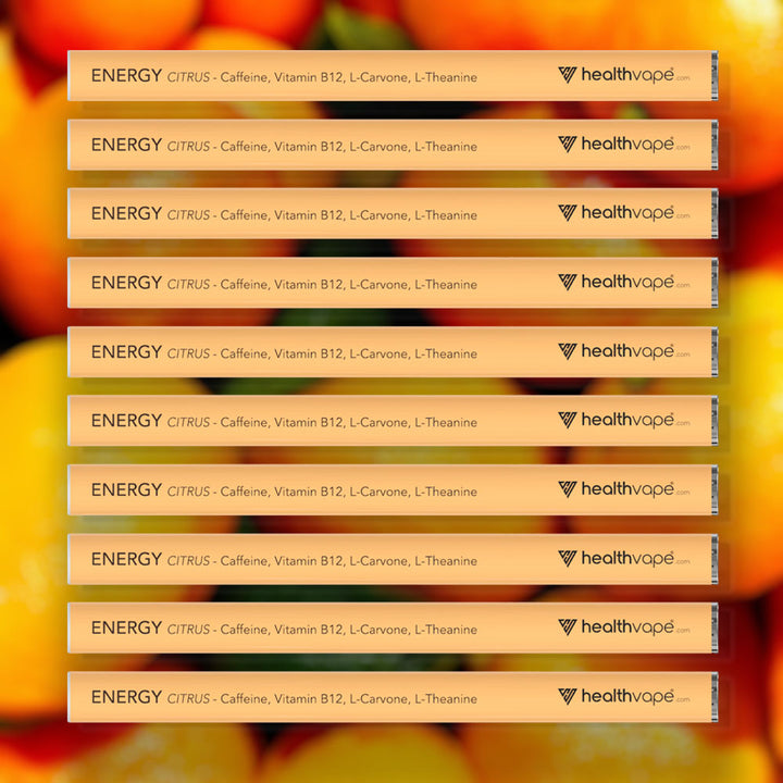 Ten HealthVape ENERGY Citrus caffeine pens stacked on orange fruit background