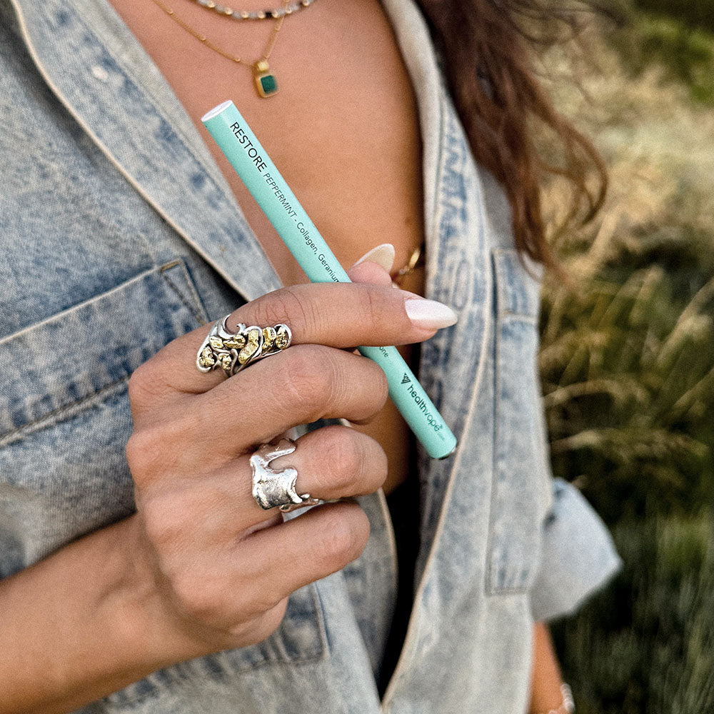 Person holding a teal HealthVape RESTORE disposable vape pen outdoors.

Image 3 (restore-lychee-03)