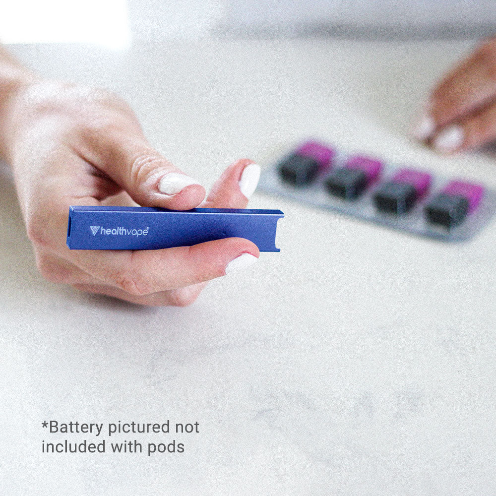 Hand holding a blue HealthVape device on light surface, pods blurred in background