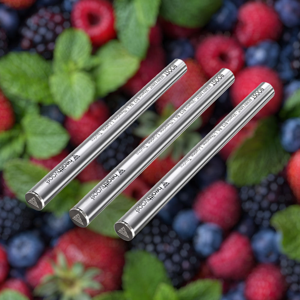Three HealthVape BOOST Berry Mint Vitamin B12 pens on a bed of fresh berries