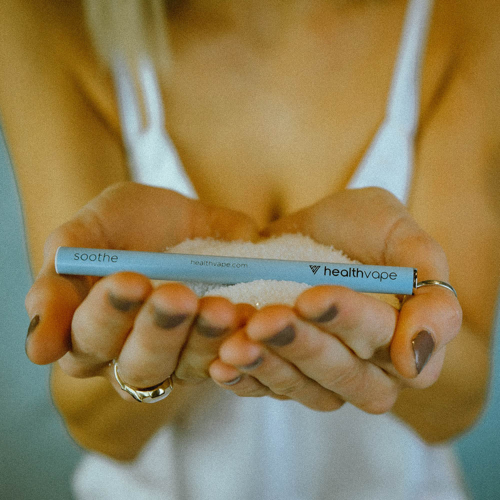 Person holding a HealthVape SOOTHE disposable inhaler in their hands, with a blurred background.